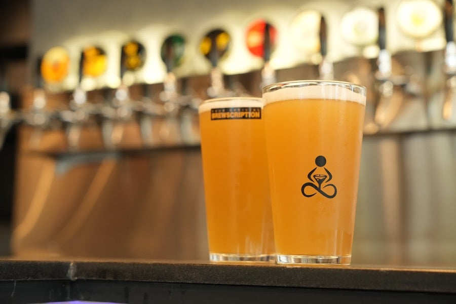 Logo pint glasses in front of the craft beer tap wall at THERAPY Borivali