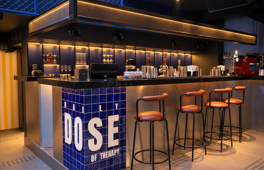 The bar at THERAPY Powai, with stools along the counter and blue tiles spelling DAILY DOSE OF THERAPY.
