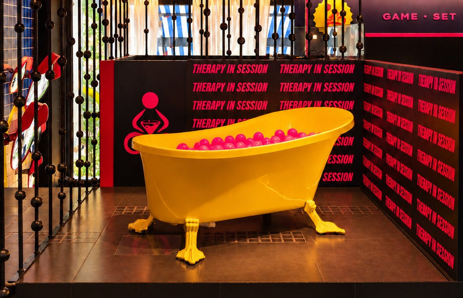 A bright yellow bathtub filled with pink balls, the photo booth at THERAPY Powai.