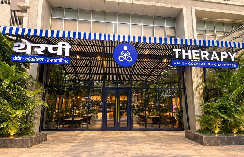 The front of THERAPY Powai: a blue and white striped awning carrying the THERAPY sign in English and Devanagari, with glass doors and palms either side.