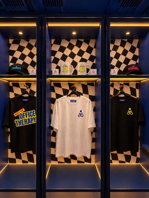 THERAPY T-shirts, caps and mugs displayed in lit lockers against a chequered wall.