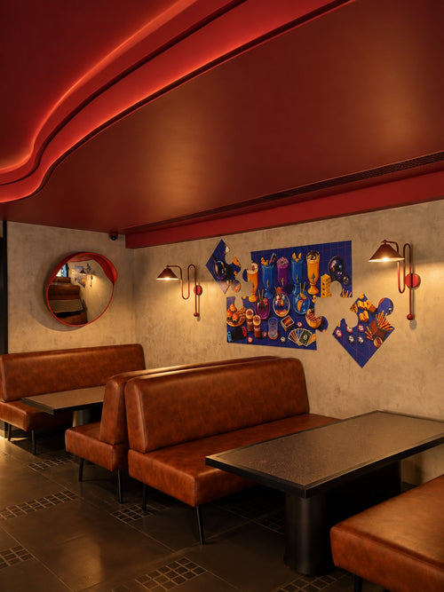 Tan leather booths under a red ceiling, with jigsaw-piece artwork on the wall.